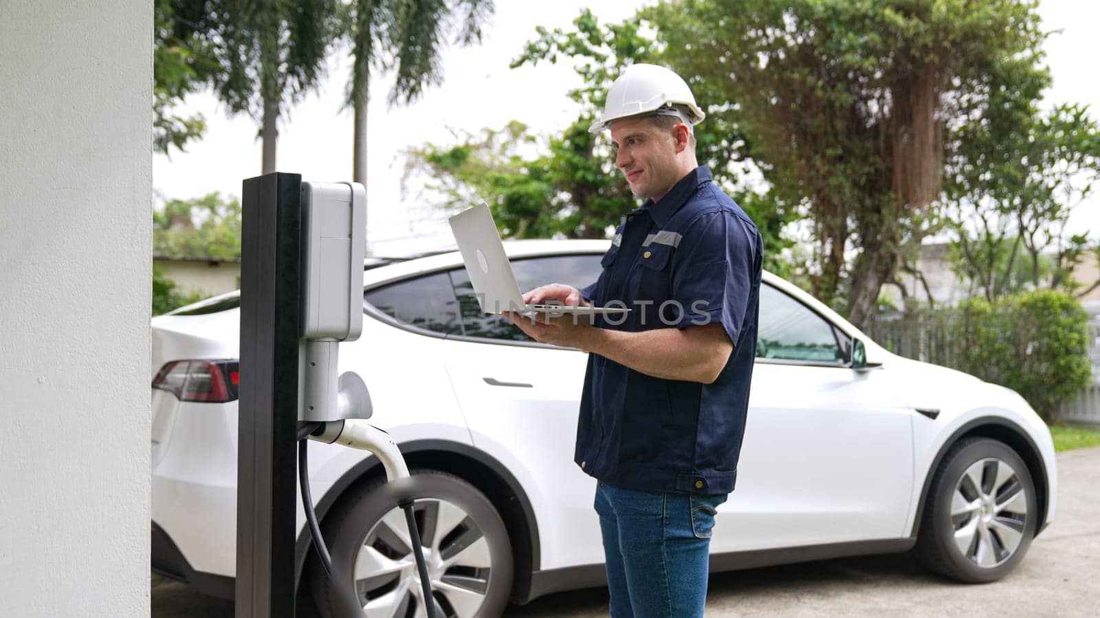 Qualified technician working with laptop for home EV station. Synchronos by biancoblue