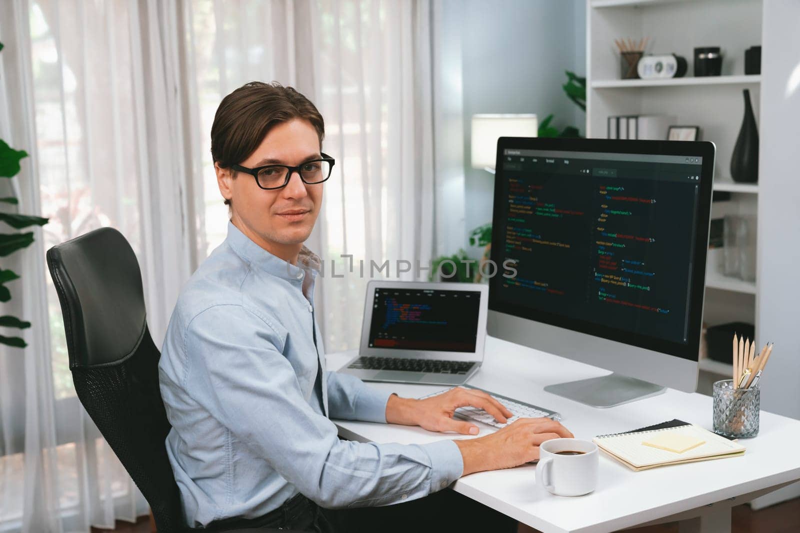 IT developer looking camera with online software development information while working on pc and laptop monitor, coding program on updated version application project creating code system. Pecuniary.