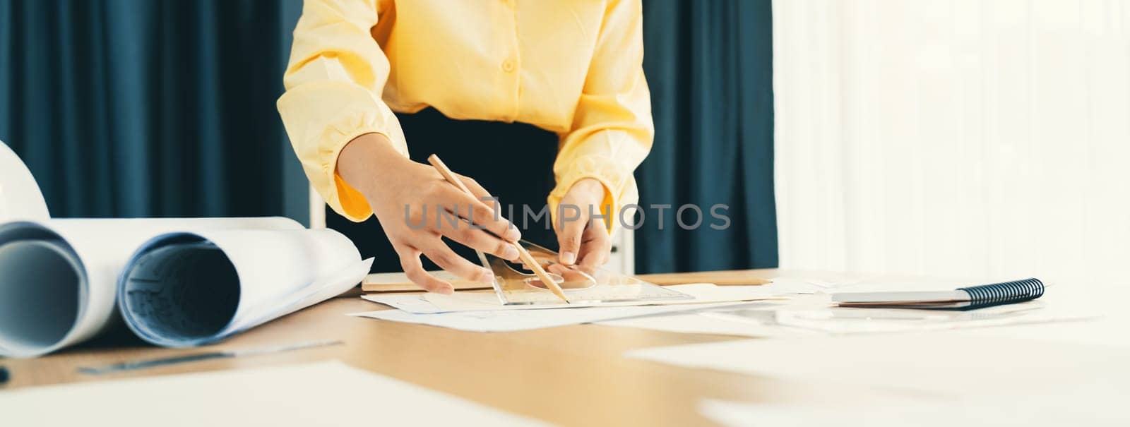 Professional architect team used divider measure during draft blueprint on table with architectural document, safety helmet and blueprint scatter around. Closeup. Focus on hand. Delineation.