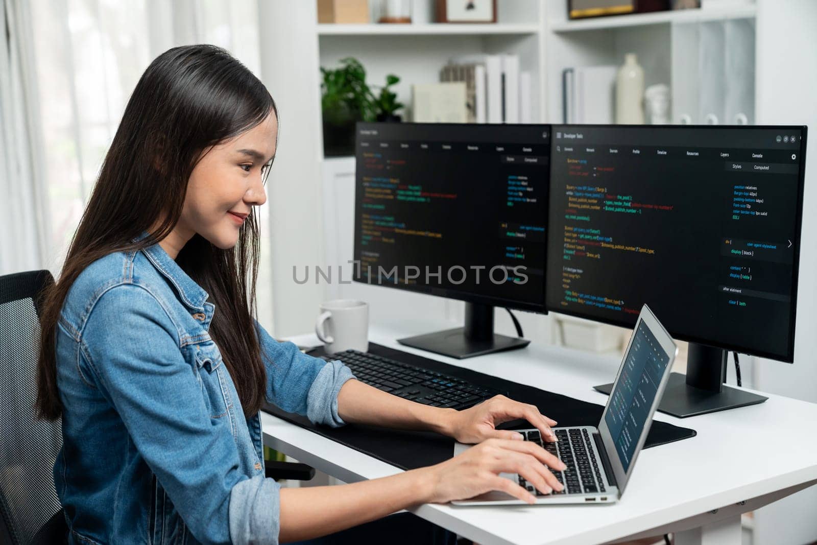 Smiling young Asian in IT developer creating with typing online information on laptop with coding program data of application, wearing jeans shirt. surrounded by safety analysis two screen. Stratagem.