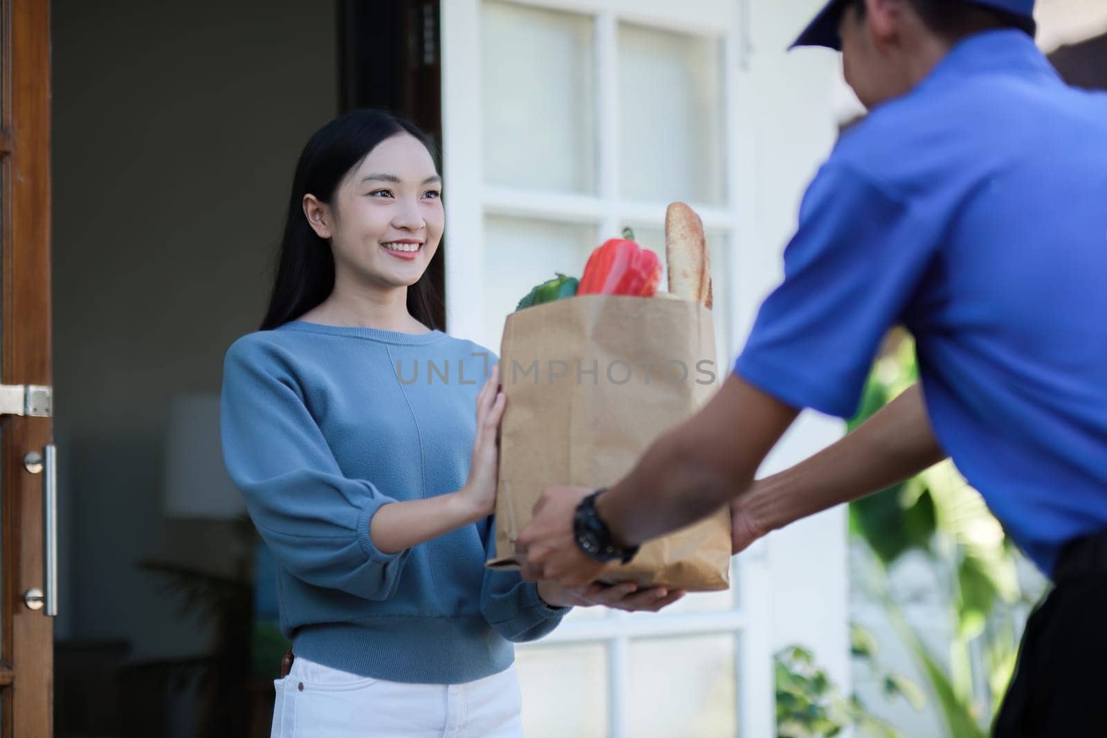 delivery man Deliver a paper bag package to the beautiful woman at the front of the house according to the order..