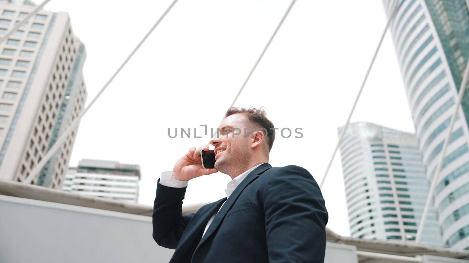 Smart caucasian businessman calling his colleague to plan financial strategy while standing at urban city. Project manager using his mobile phone to communicate with marketing team. Lifestyle. Urbane.