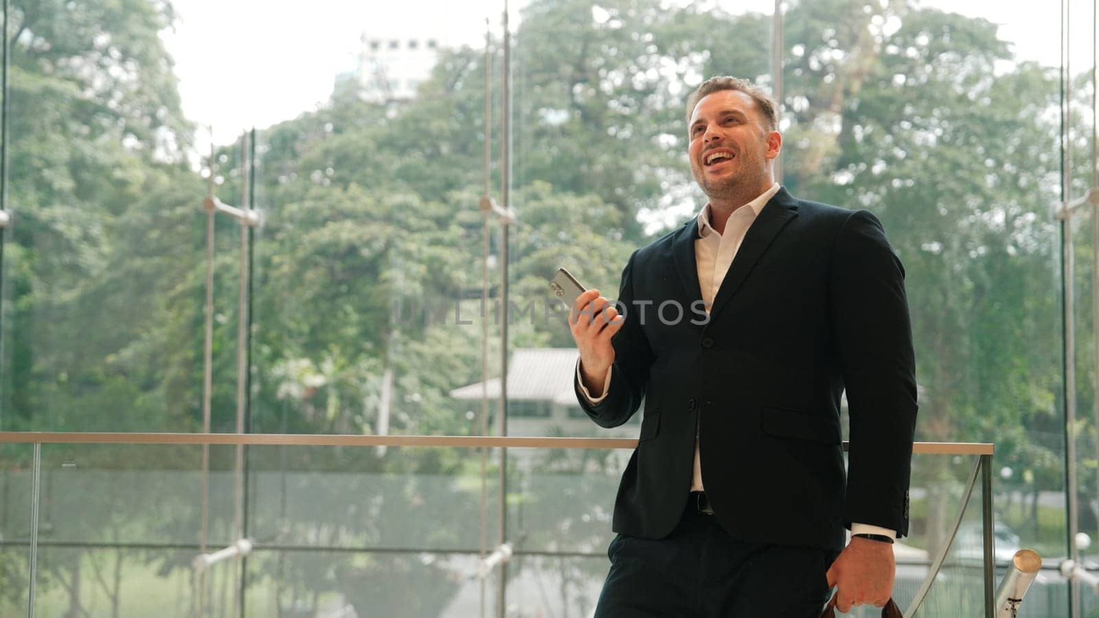 Caucasian businessman calling manager by using smart phone and discuss about financial report. Male leader talking marketing team by using telephone while standing at stair in modern building. Urbane.