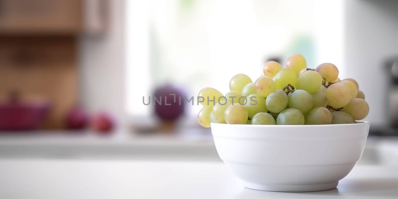 Light grapes bowl on the kitchen table with blurred background by GekaSkr