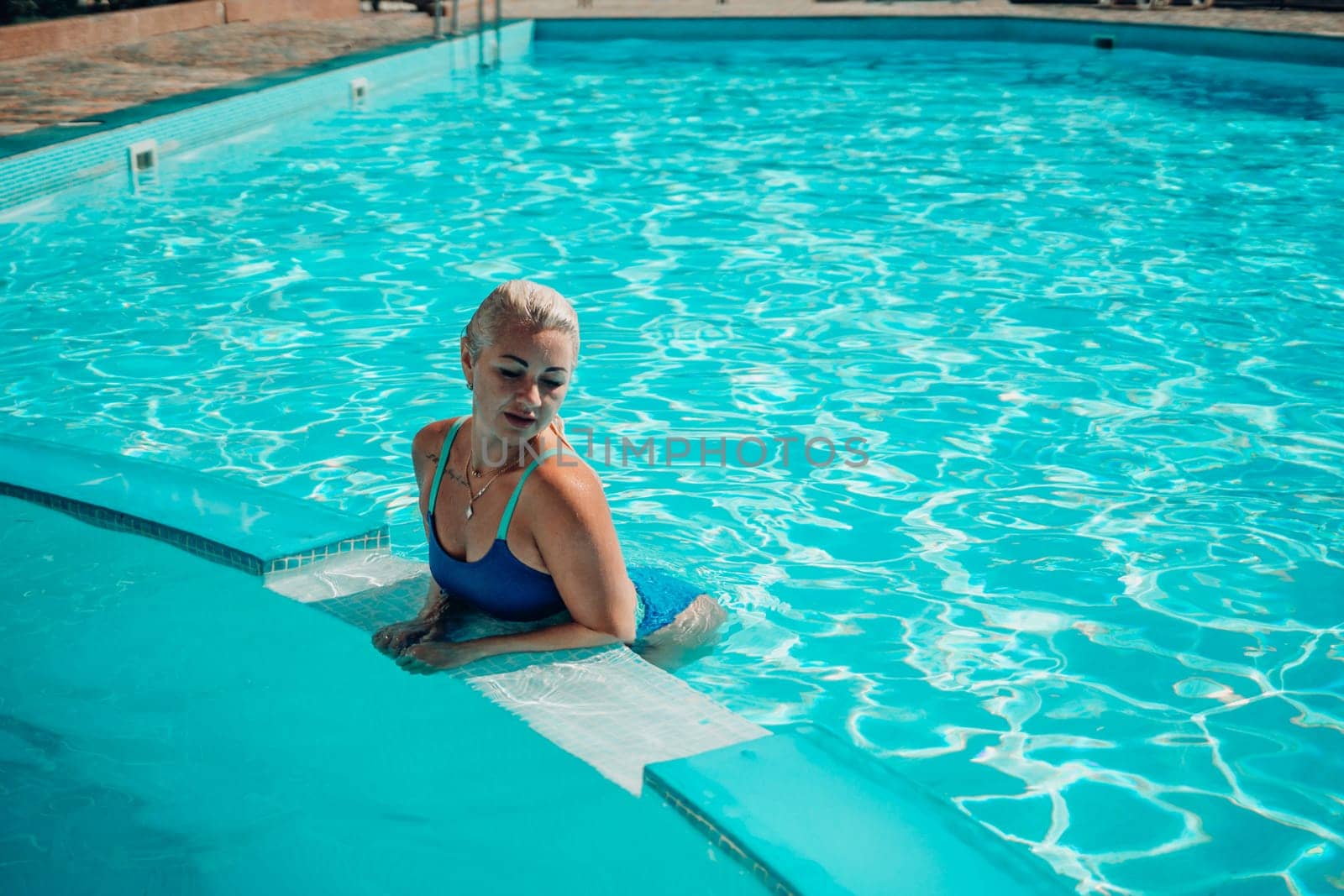 woman swimming pool. happy woman with wet hair and stylish sunglasses sunbathing in pool by Matiunina