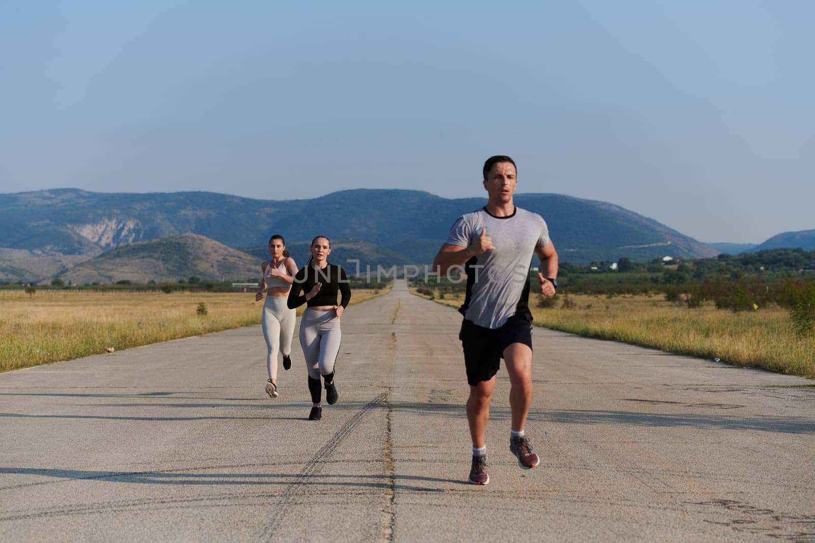 A group of friends maintains a healthy lifestyle by running outdoors on a sunny day, bonding over fitness and enjoying the energizing effects of exercise and nature by dotshock