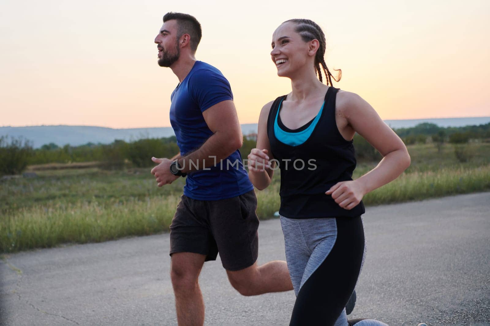 A vibrant couple dashes running the outdoors, embodying the essence of athleticism and romance, their confident strides reflecting a shared commitment to fitness and preparation for future marathon challenges.