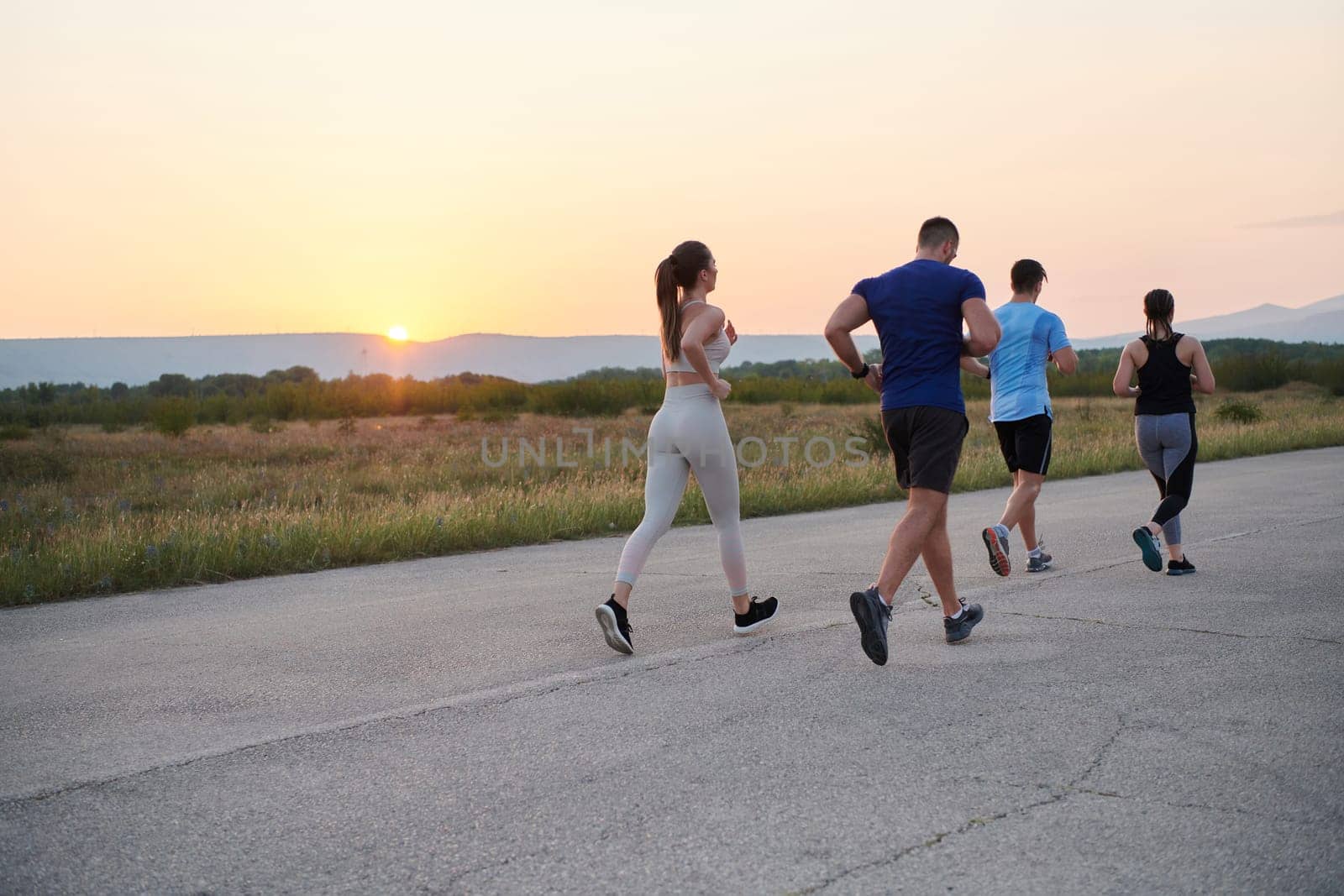 A diverse group of runners trains together at sunset. by dotshock