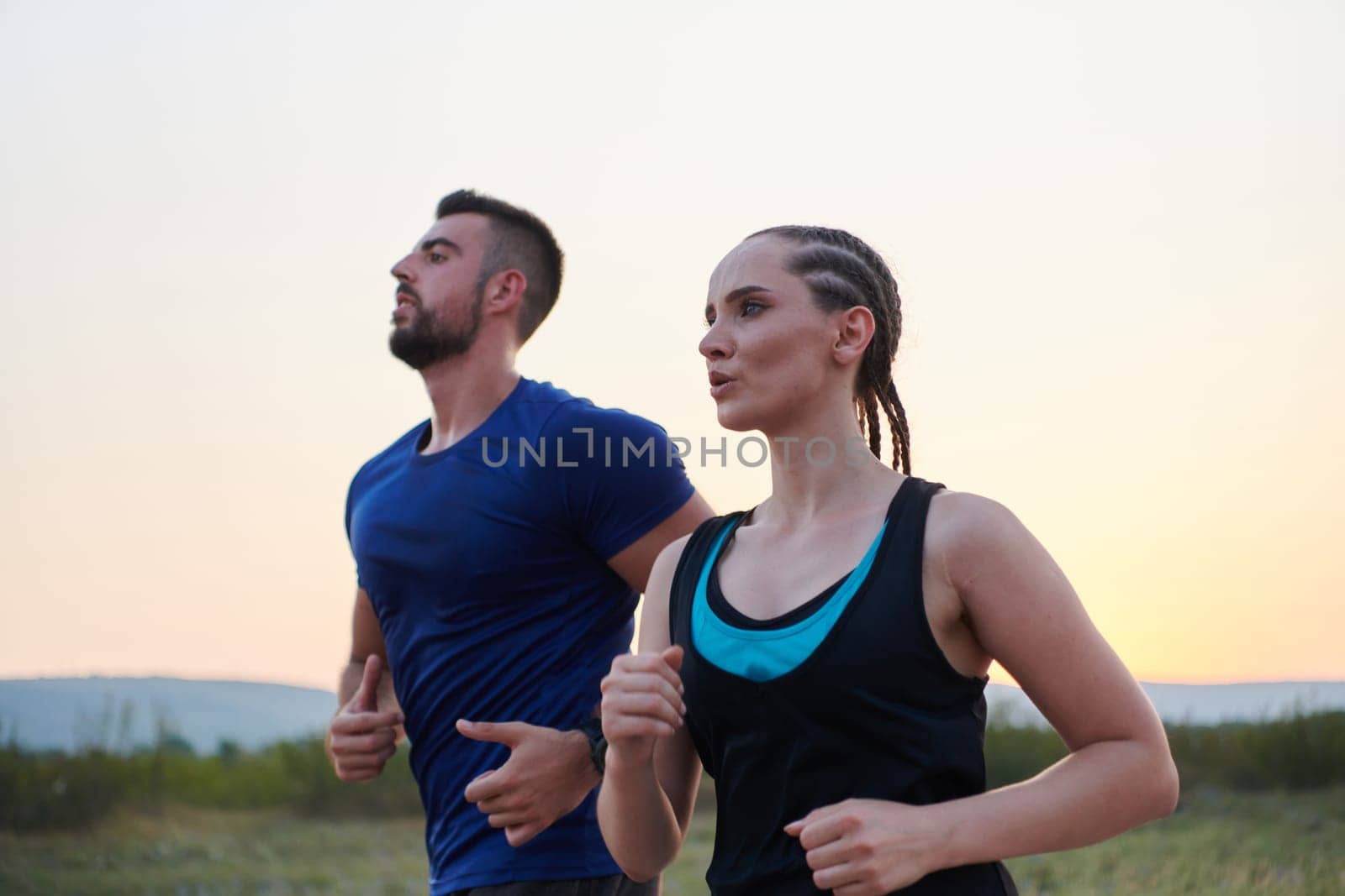 A vibrant couple dashes running the outdoors, embodying the essence of athleticism and romance, their confident strides reflecting a shared commitment to fitness and preparation for future marathon challenges.