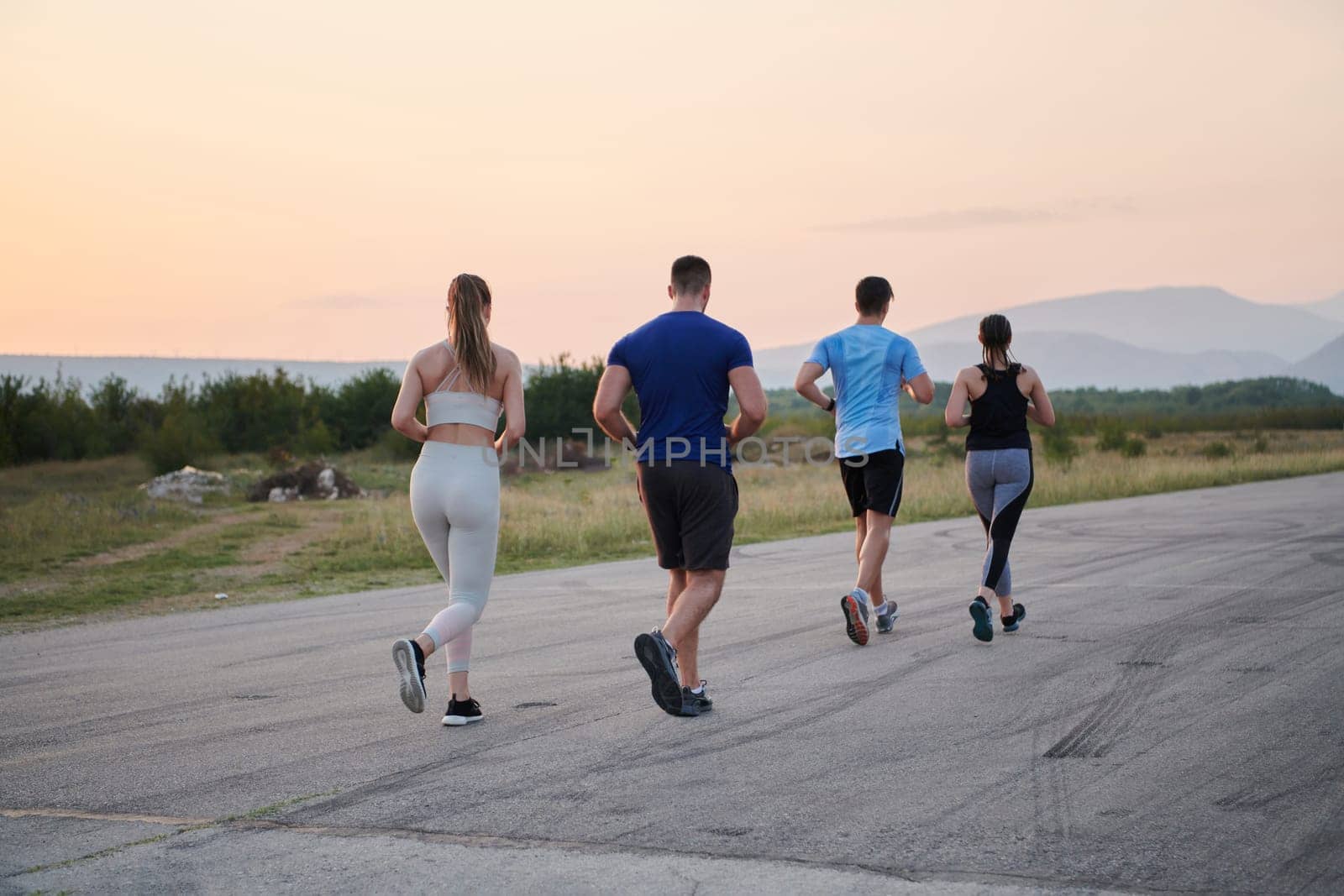 A group of friends maintains a healthy lifestyle by running outdoors on a sunny day, bonding over fitness and enjoying the energizing effects of exercise and nature by dotshock