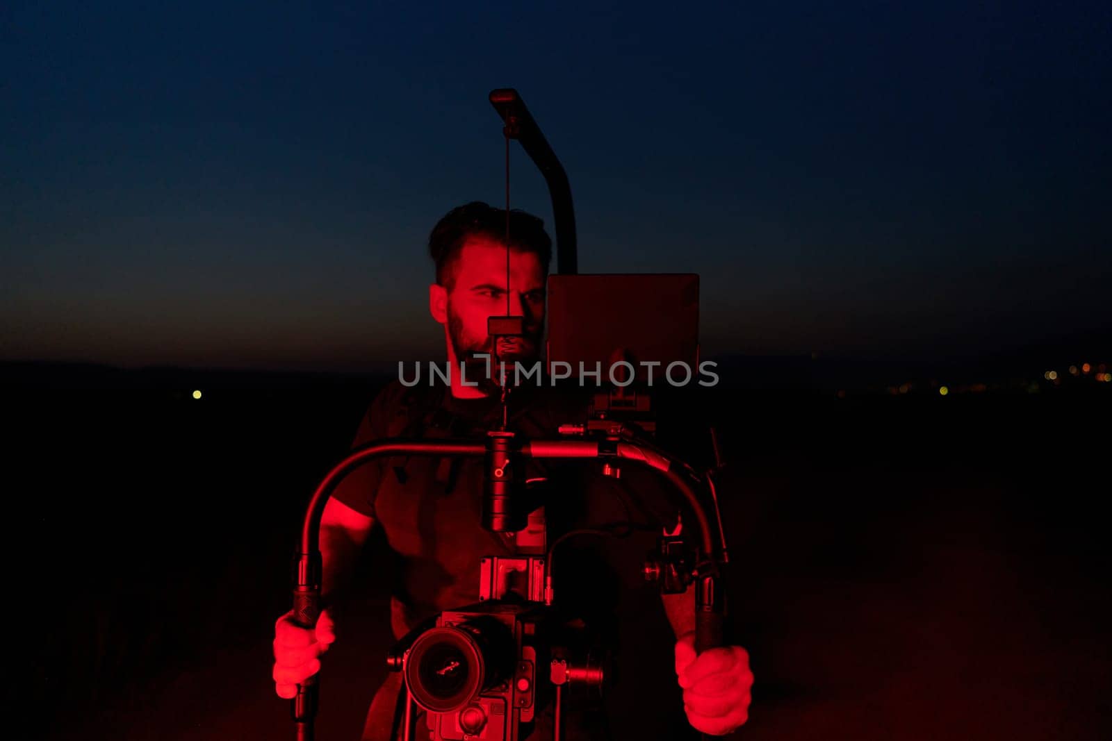 A skilled videographer captures the intensity of athletes running, illuminated by vibrant red lights, encapsulating the energy and determination of their nighttime training session.