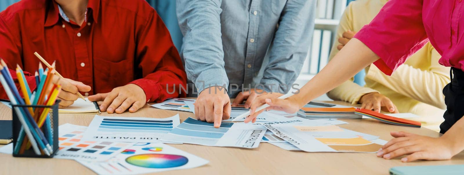 A cropped image of professional interior designer discuss the color material with her colleagues by comparing with color swatches and color palette document. Creative design concept. Variegated.