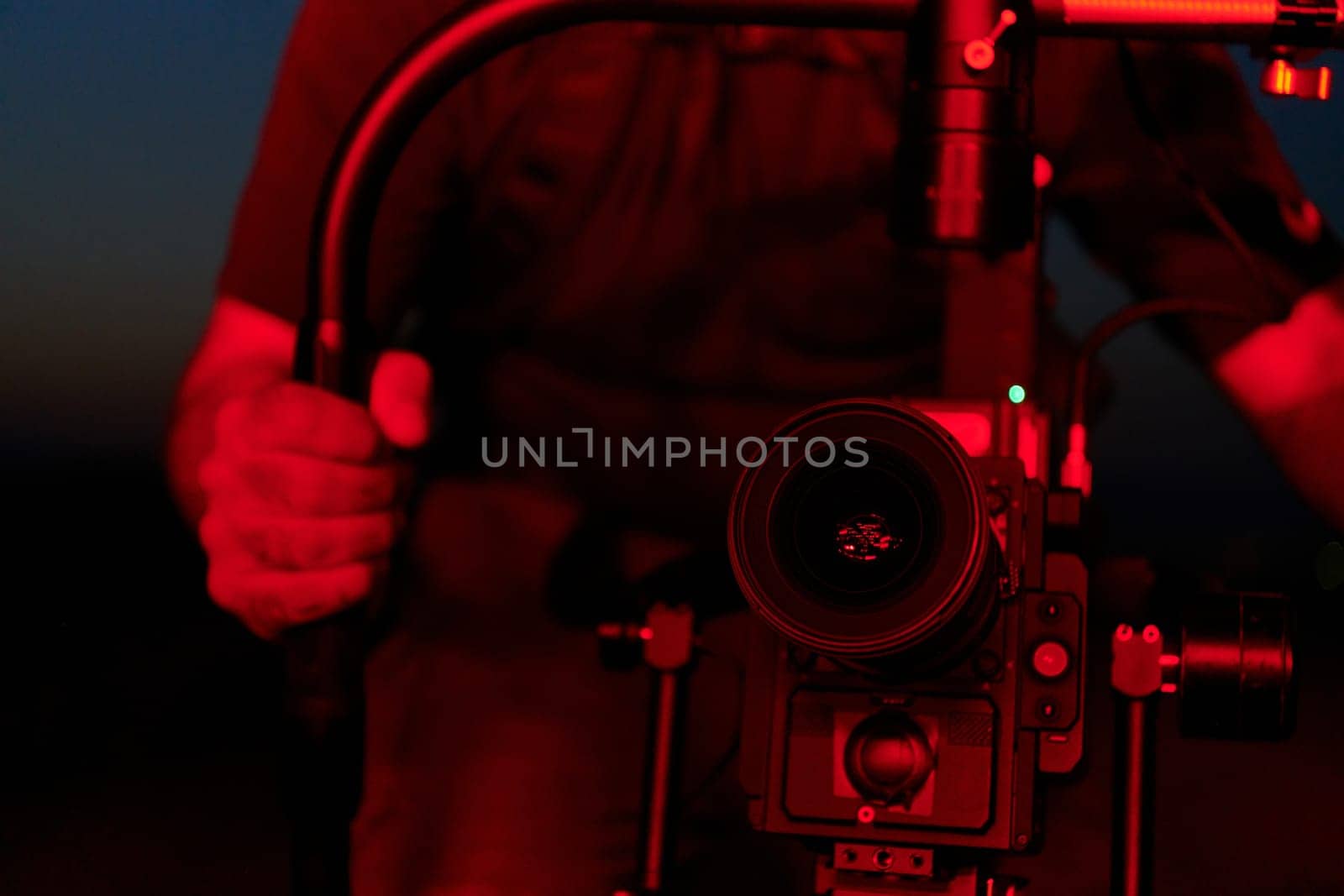 A skilled videographer captures the intensity of athletes running, illuminated by vibrant red lights, encapsulating the energy and determination of their nighttime training session.