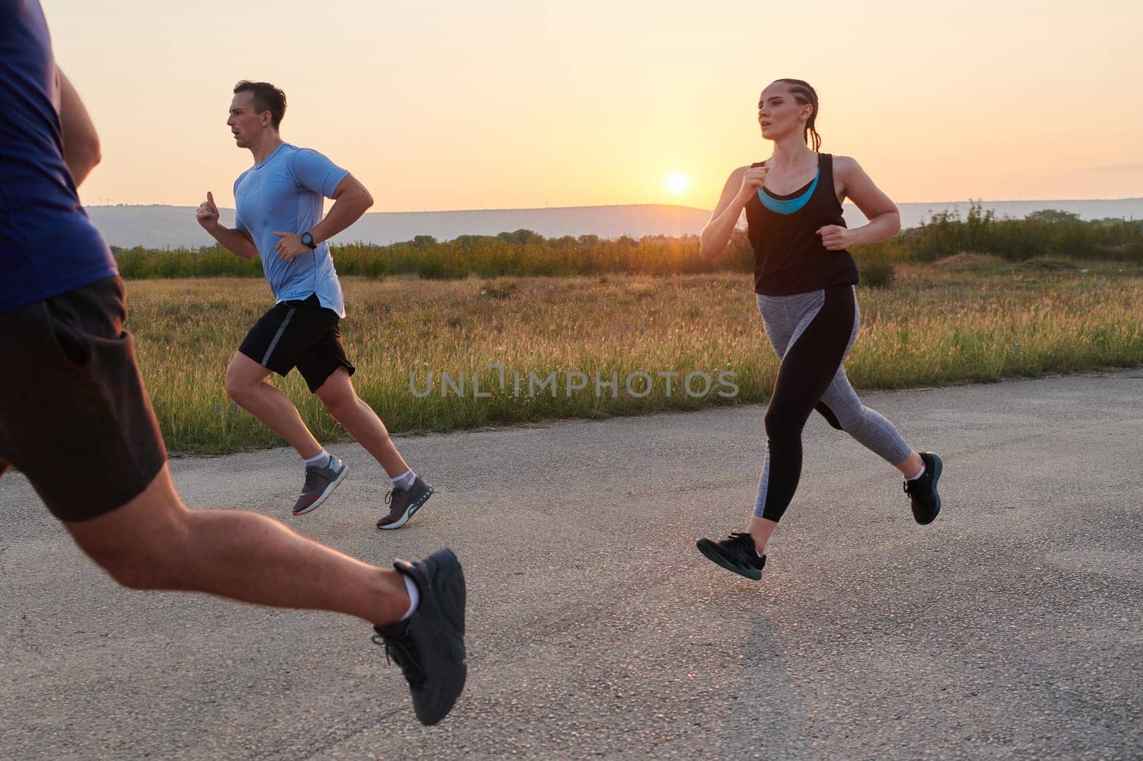 A diverse group of runners trains together at sunset. by dotshock