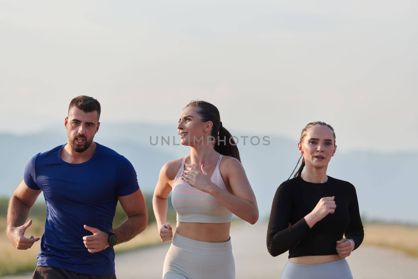 A group of friends maintains a healthy lifestyle by running outdoors on a sunny day, bonding over fitness and enjoying the energizing effects of exercise and nature by dotshock