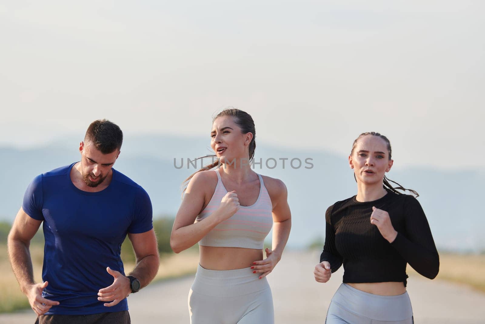 A group of friends maintains a healthy lifestyle by running outdoors on a sunny day, bonding over fitness and enjoying the energizing effects of exercise and nature.