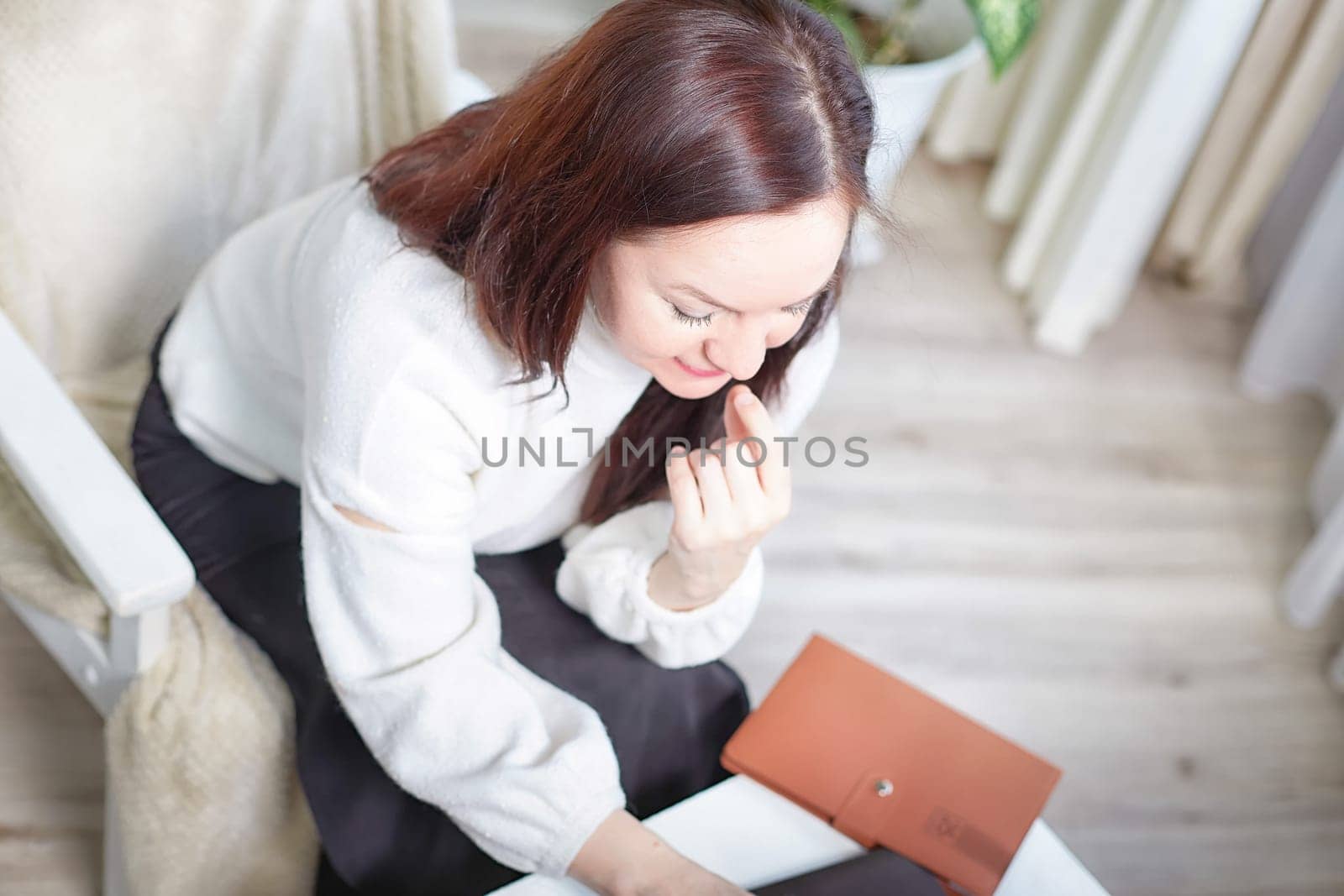 Confident middle aged Business woman in White Turtleneck with Notebook in cozy room. A professional mature woman ready for meeting