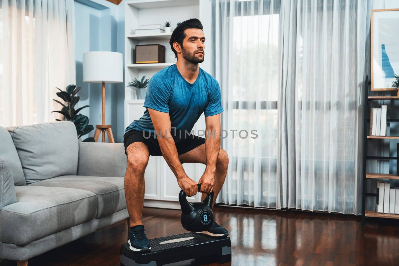 Athletic body and active sporty man doing squat with kettlebell weight for effective targeting muscle gain at gaiety home as concept of healthy fit body home workout lifestyle.