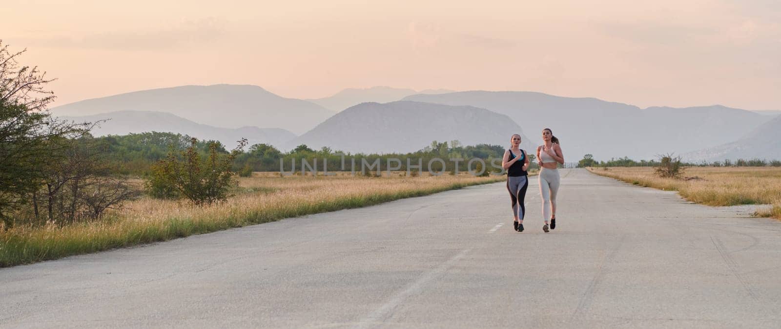 On a beautiful sunny day, two athletic friends enjoy a run together, maintaining their healthy lifestyle and fitness regimen.