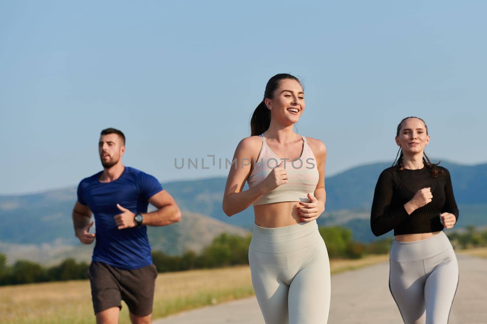 A group of friends maintains a healthy lifestyle by running outdoors on a sunny day, bonding over fitness and enjoying the energizing effects of exercise and nature.