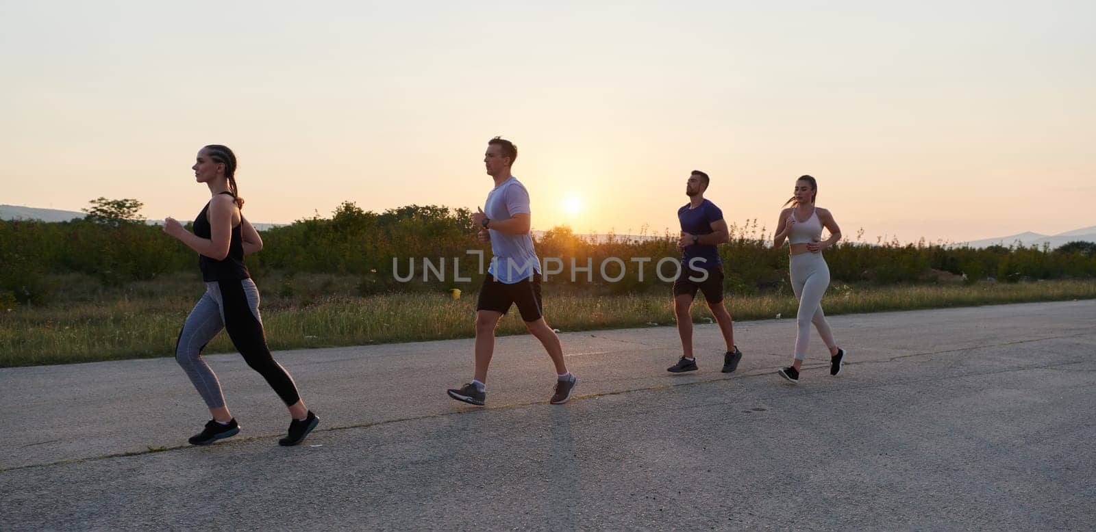 A diverse group of runners trains together at sunset. by dotshock