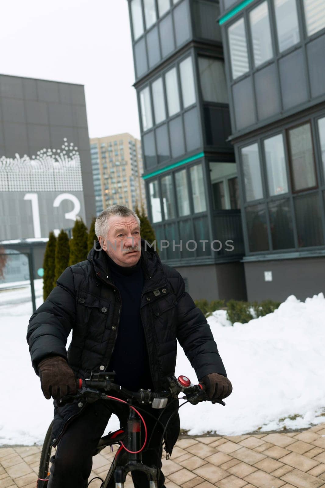 European elderly man leading a healthy lifestyle and riding a bicycle in winter.