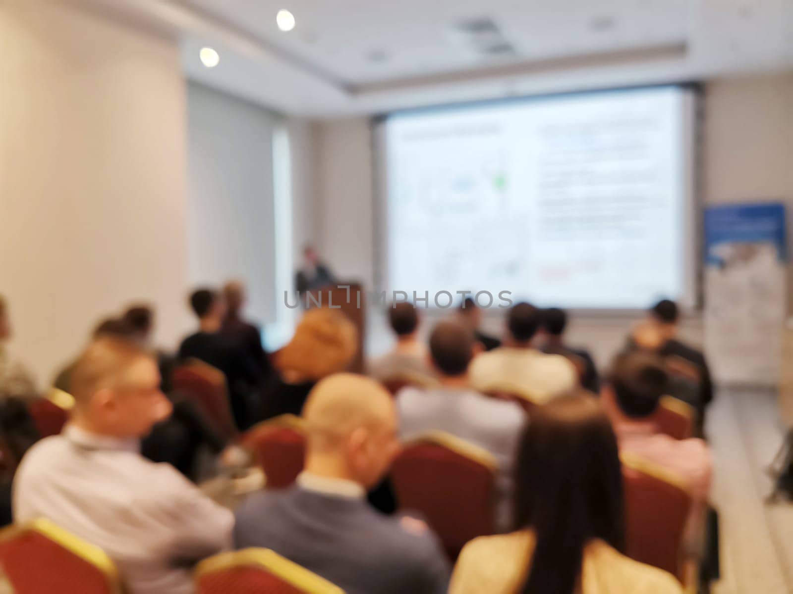 Blurred background image of audience in a business conference or seminar. Audience listens to the lecturer at the conference in auditorium.