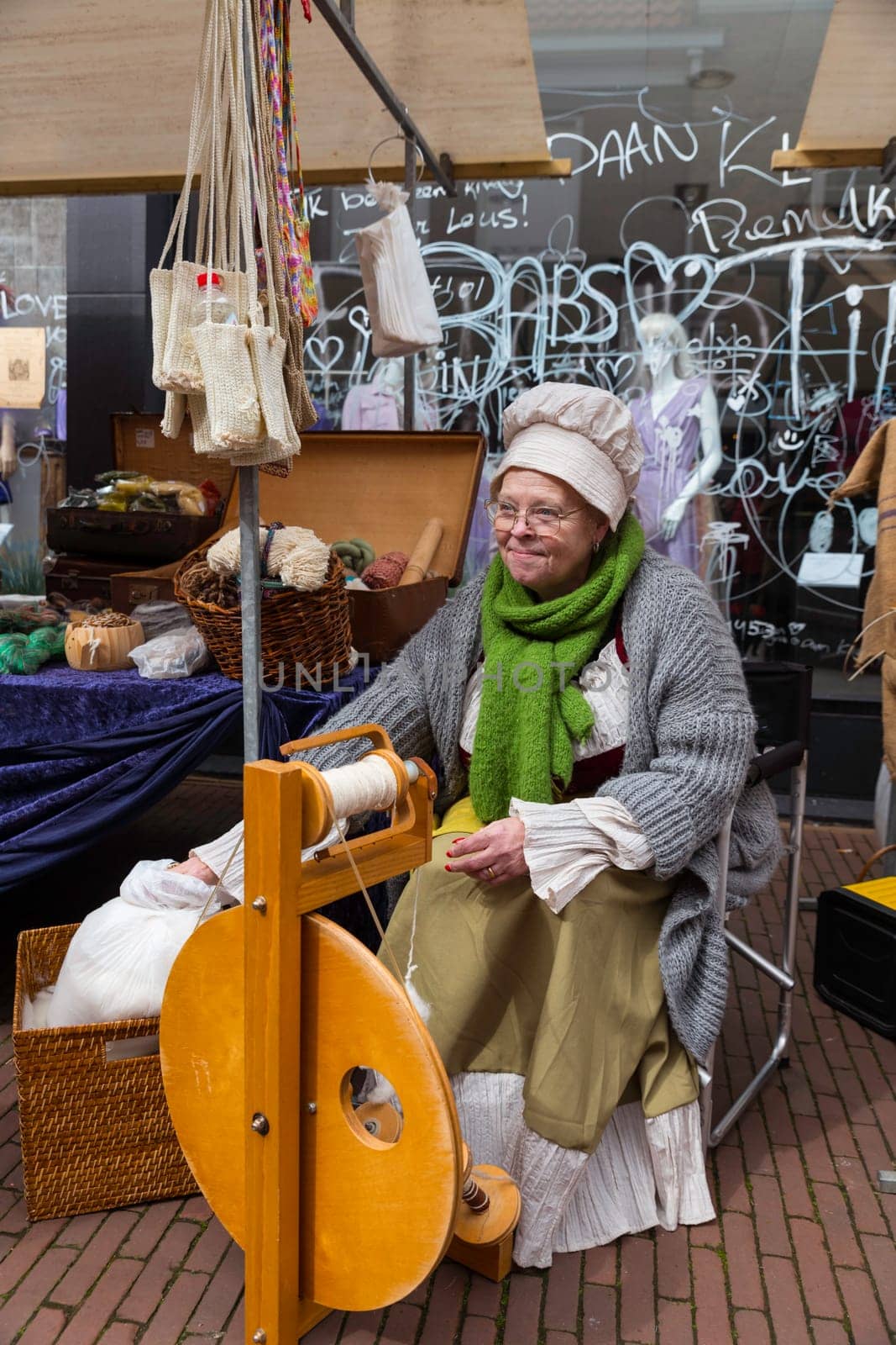 Brielle,Holland,1-04-2024:a woman in traditional costume is spinning on a spinning wheel during the celebration of the the first town to be liberated from the Spanish in Den Briel in the Netherlands