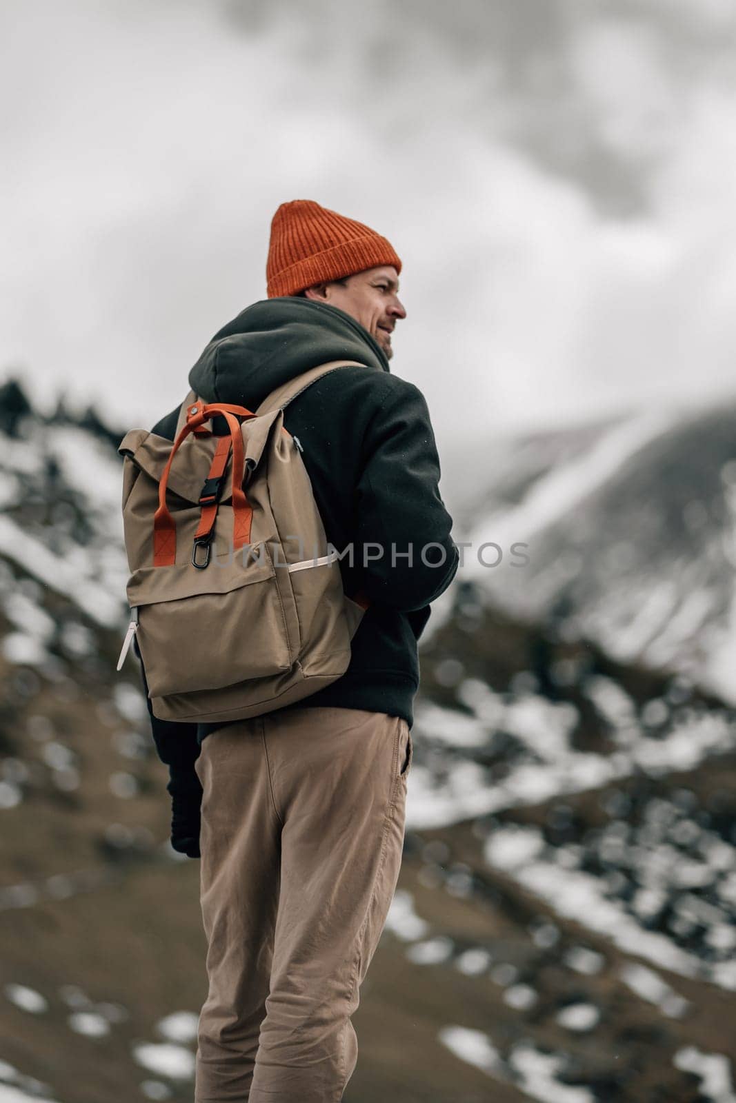 With a rugged terrain before him, a hiker stands ready to embrace the wild, snow-laden landscape.