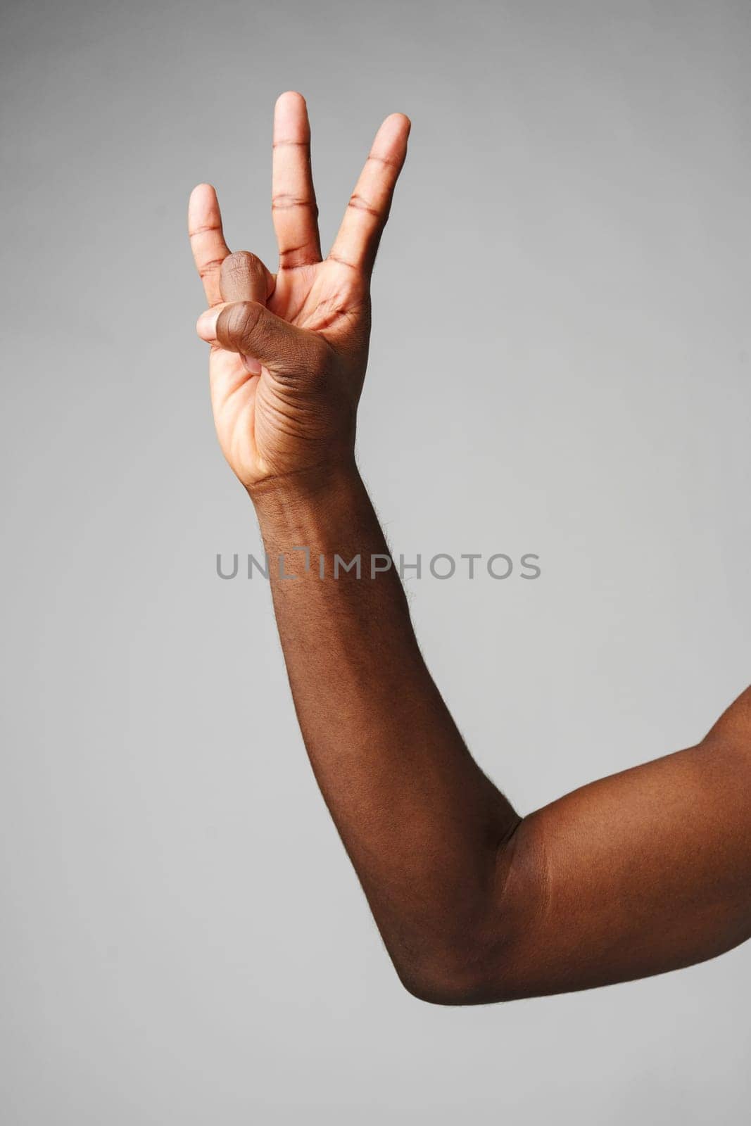 A mans arm is extended, with his hand forming a peace sign gesture.