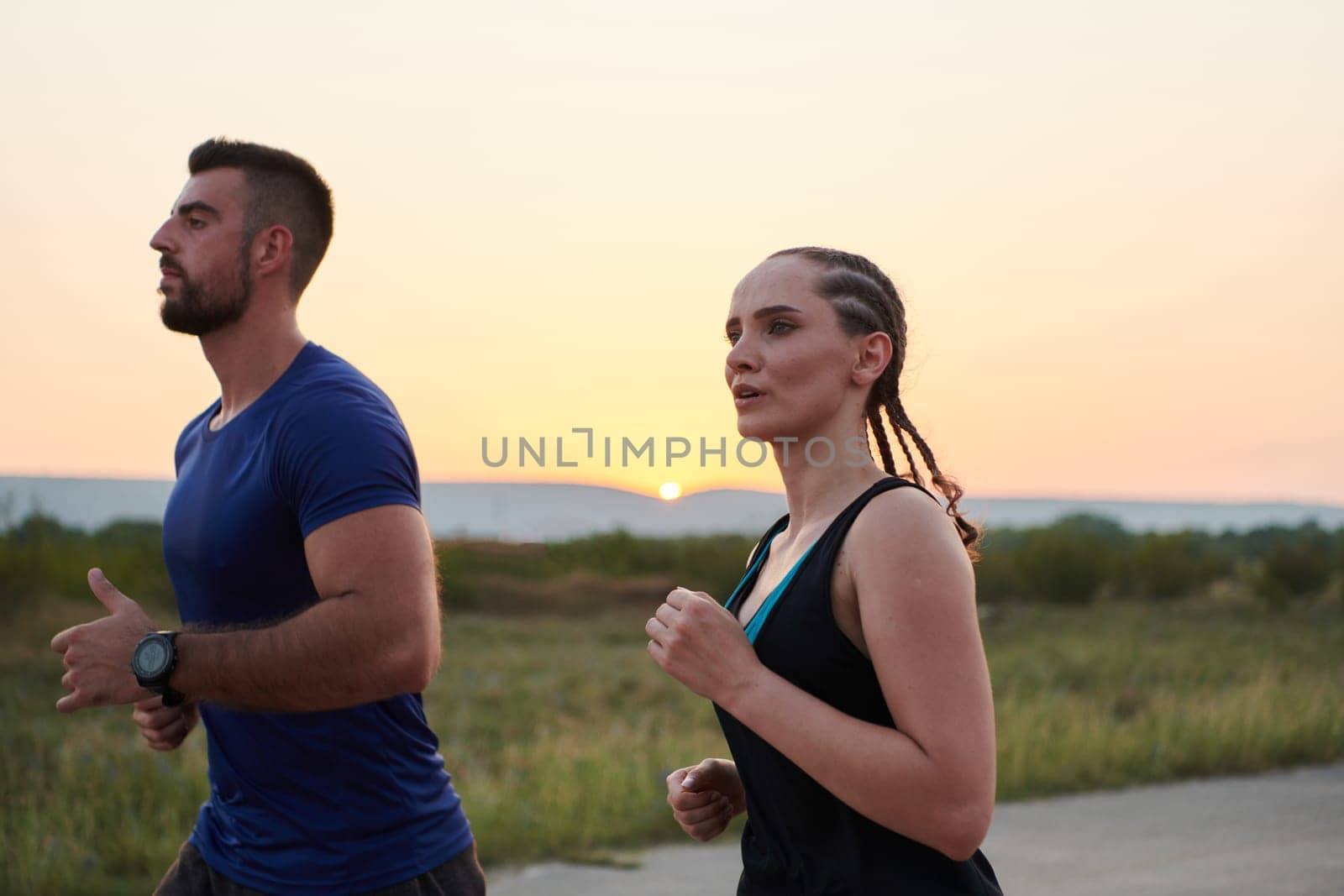 A vibrant couple dashes running the outdoors, embodying the essence of athleticism and romance, their confident strides reflecting a shared commitment to fitness and preparation for future marathon challenges.