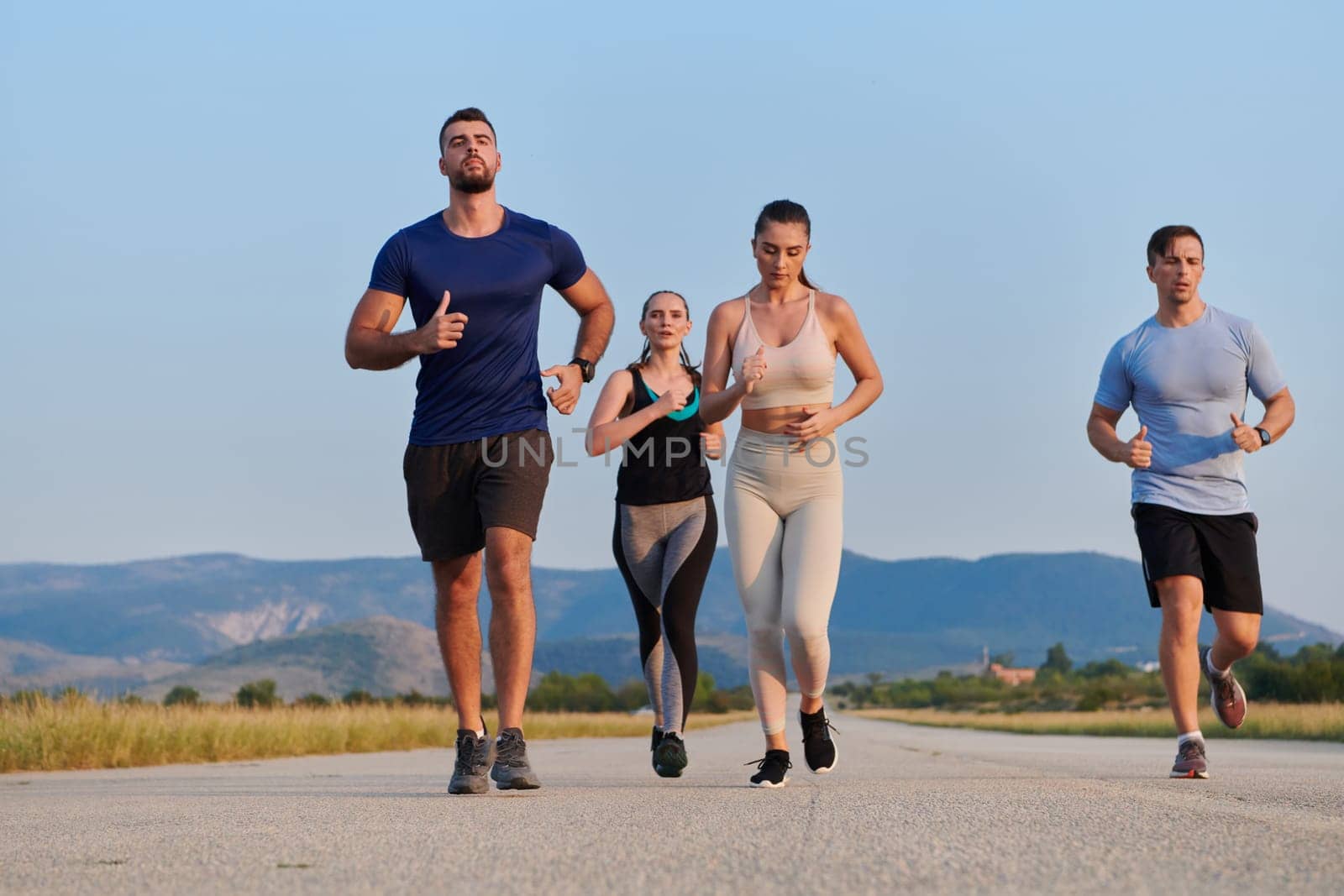 A group of friends maintains a healthy lifestyle by running outdoors on a sunny day, bonding over fitness and enjoying the energizing effects of exercise and nature by dotshock