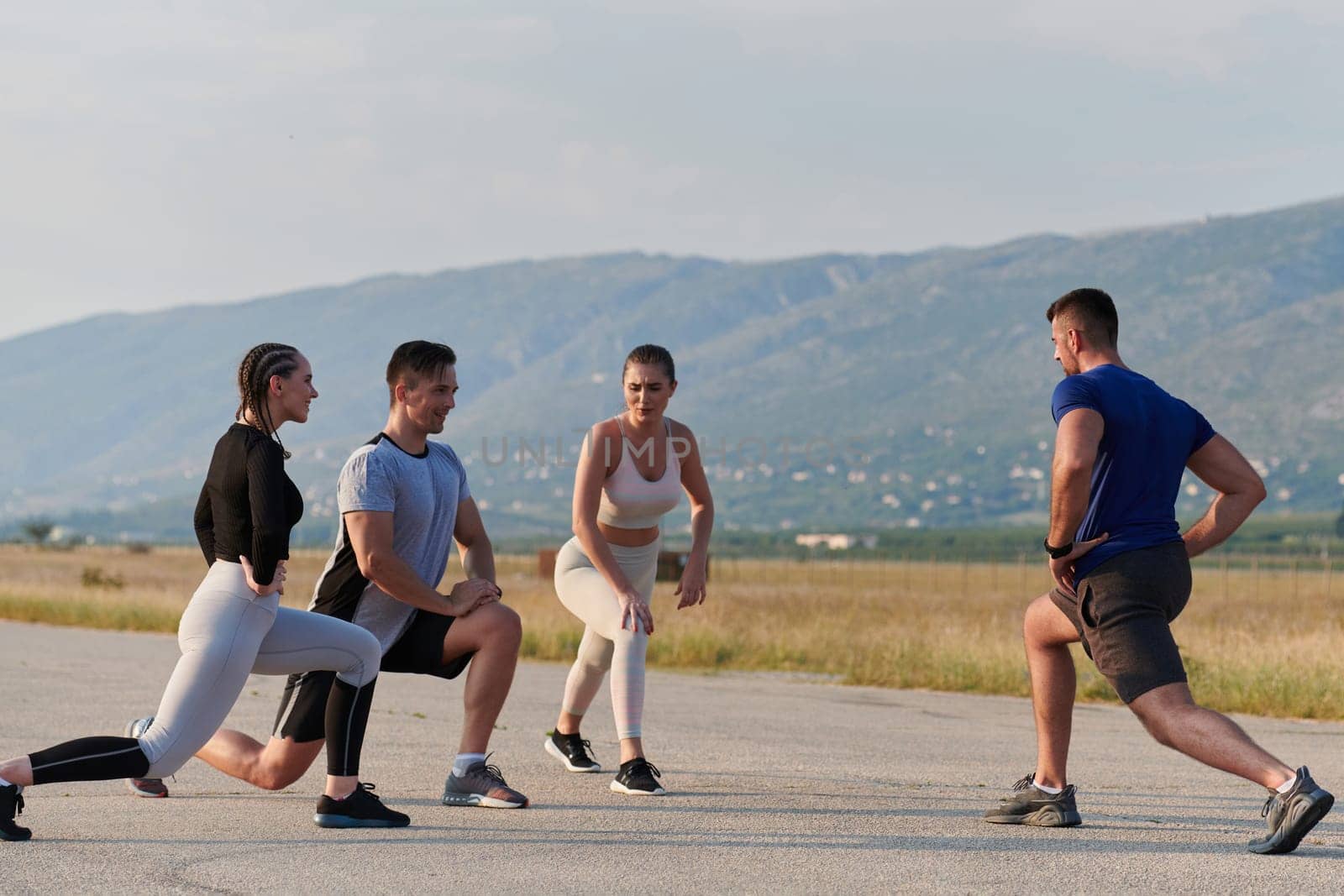 A determined group of athletes engage in a collective stretching session before their run, fostering teamwork and preparation in pursuit of their fitness goals.