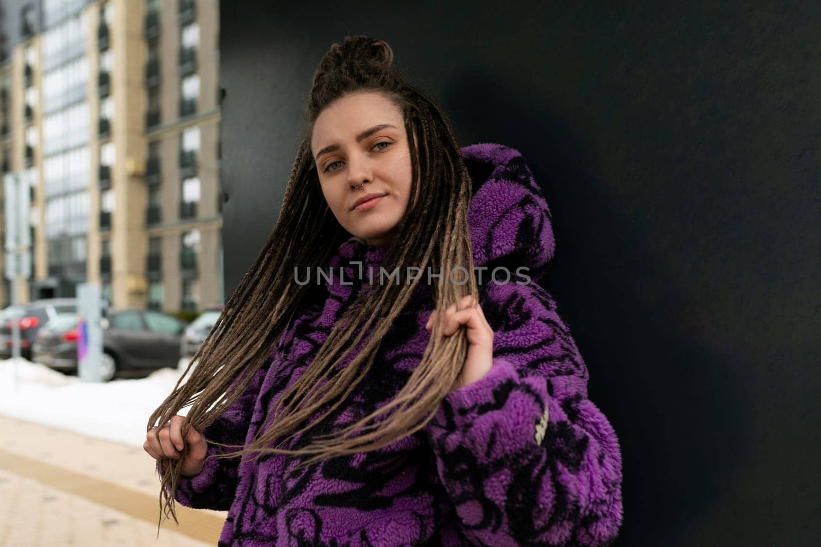 Beautiful young woman in an informal look with dreadlocks against the background of the street.