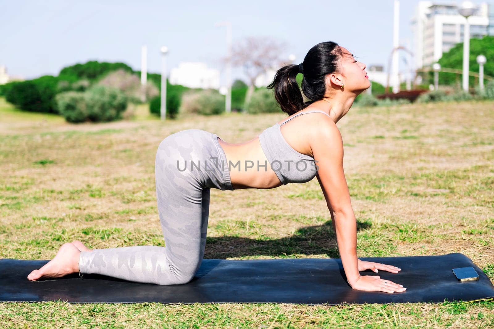 young asian woman doing back stretching exercises with cow pose on her yoga mat, active and healthy lifestyle concept