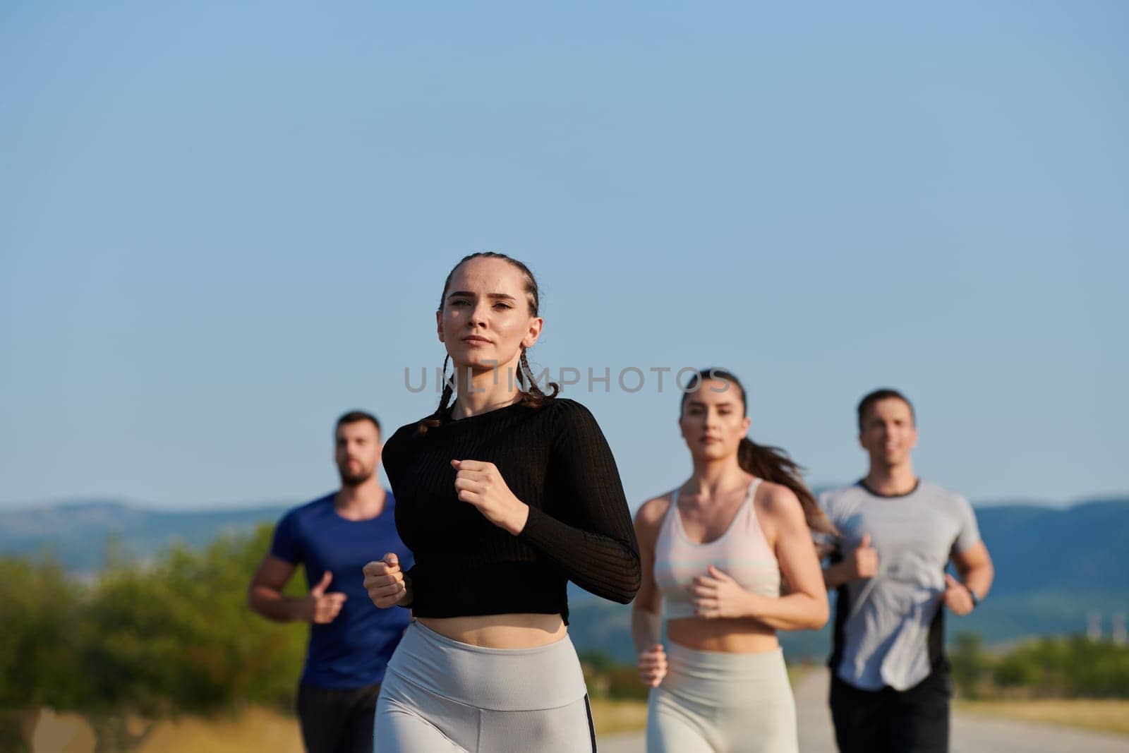 A group of friends maintains a healthy lifestyle by running outdoors on a sunny day, bonding over fitness and enjoying the energizing effects of exercise and nature.