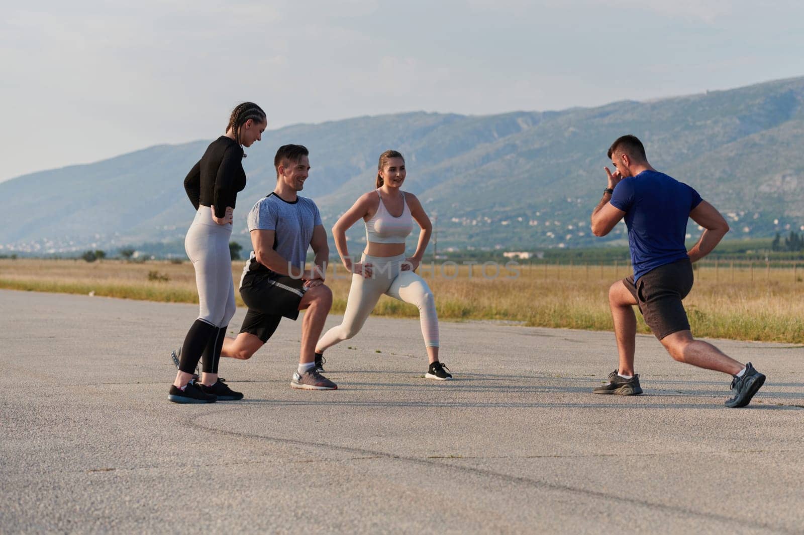 A determined group of athletes engage in a collective stretching session before their run, fostering teamwork and preparation in pursuit of their fitness goals.