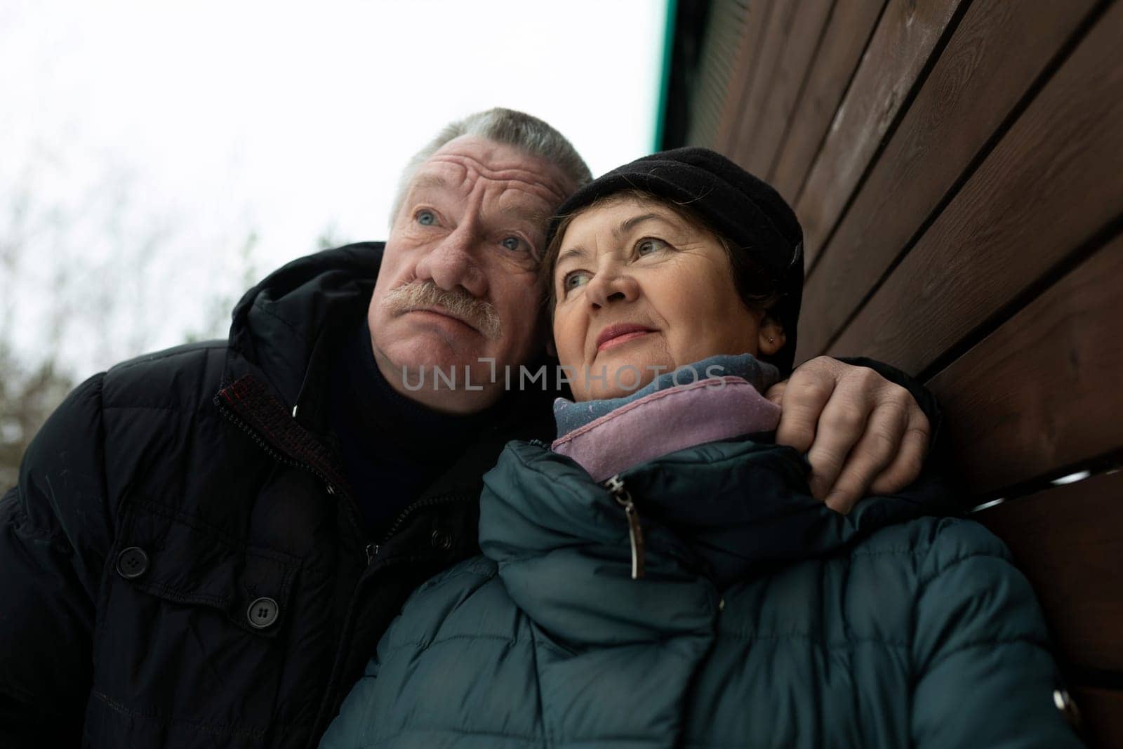 Cute couple of pensioners walking down the street in the cold season by TRMK