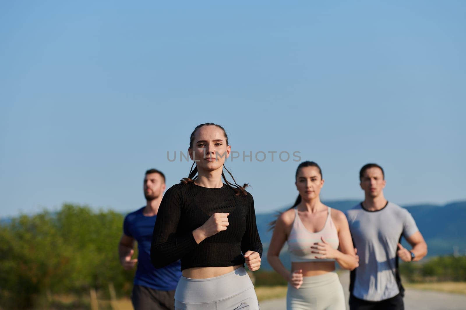 A group of friends maintains a healthy lifestyle by running outdoors on a sunny day, bonding over fitness and enjoying the energizing effects of exercise and nature by dotshock