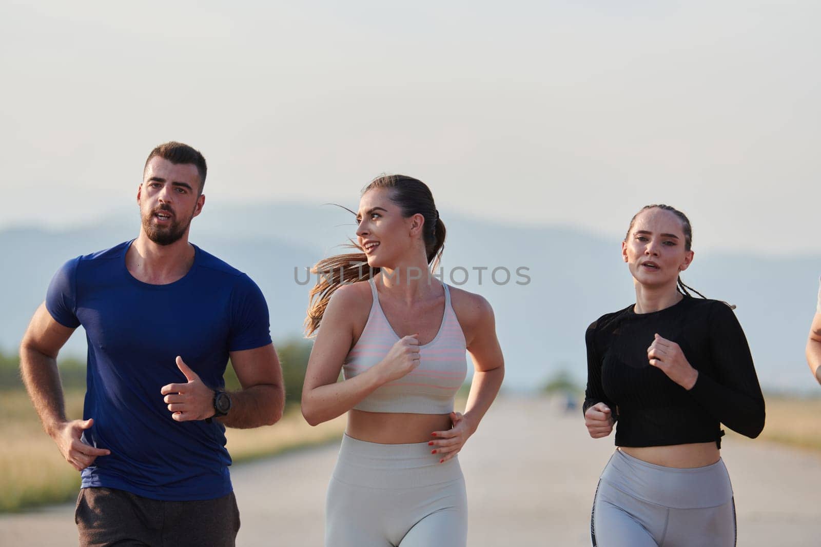 A group of friends maintains a healthy lifestyle by running outdoors on a sunny day, bonding over fitness and enjoying the energizing effects of exercise and nature by dotshock