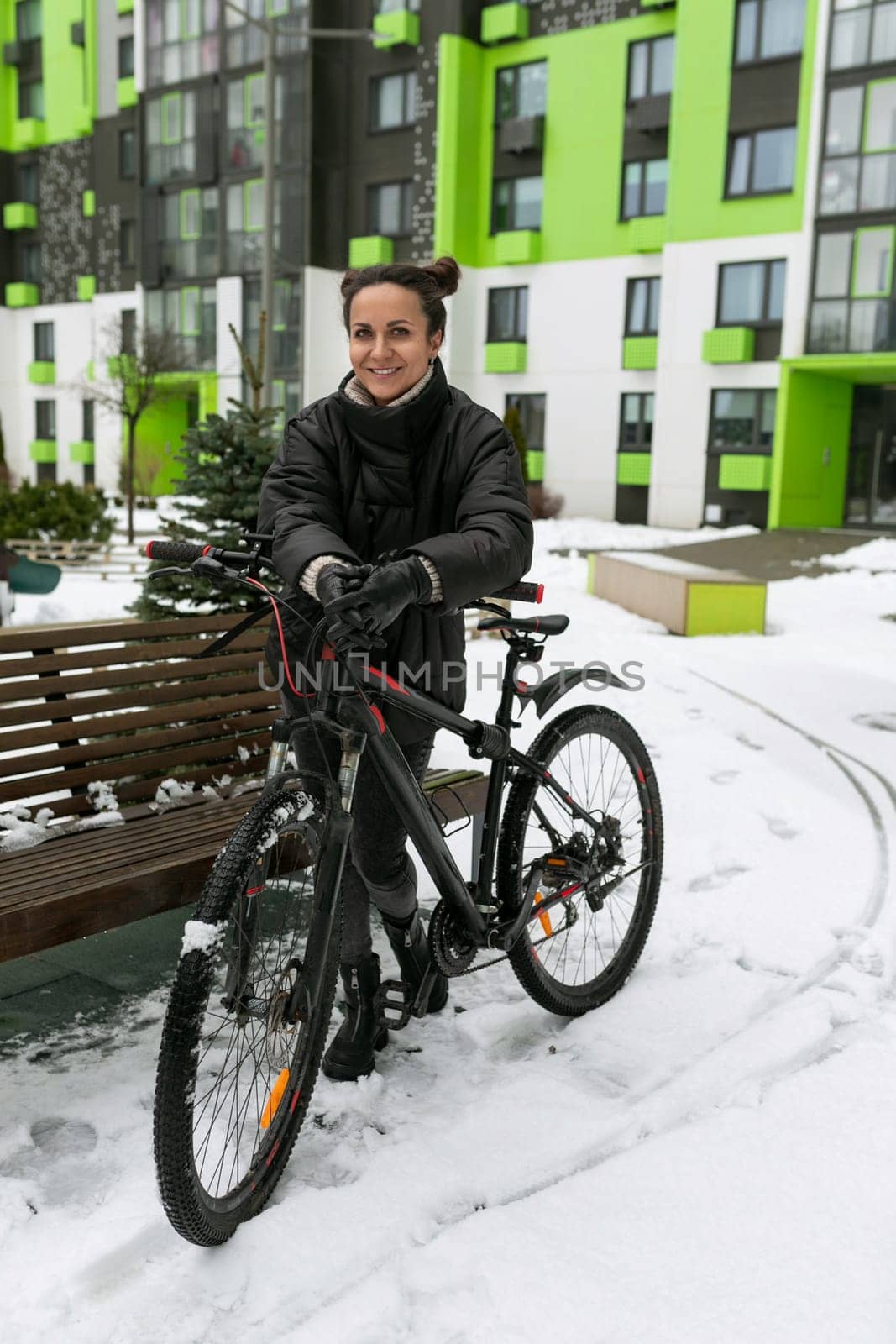 Sports concept, young woman with a bicycle on the background of a high-rise building.