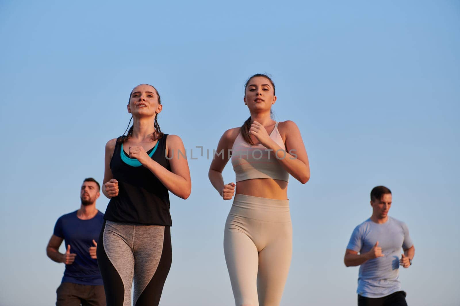 A group of friends maintains a healthy lifestyle by running outdoors on a sunny day, bonding over fitness and enjoying the energizing effects of exercise and nature by dotshock