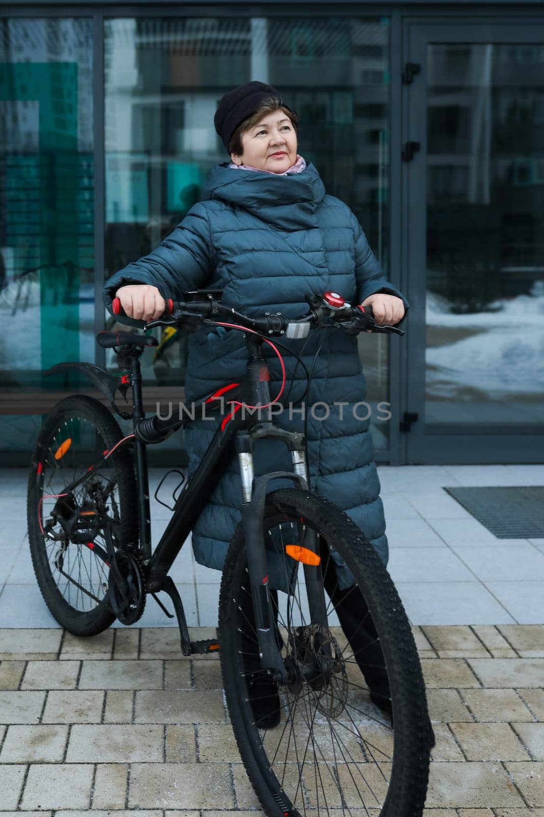 Mature European woman goes for a walk with a bicycle in winter.