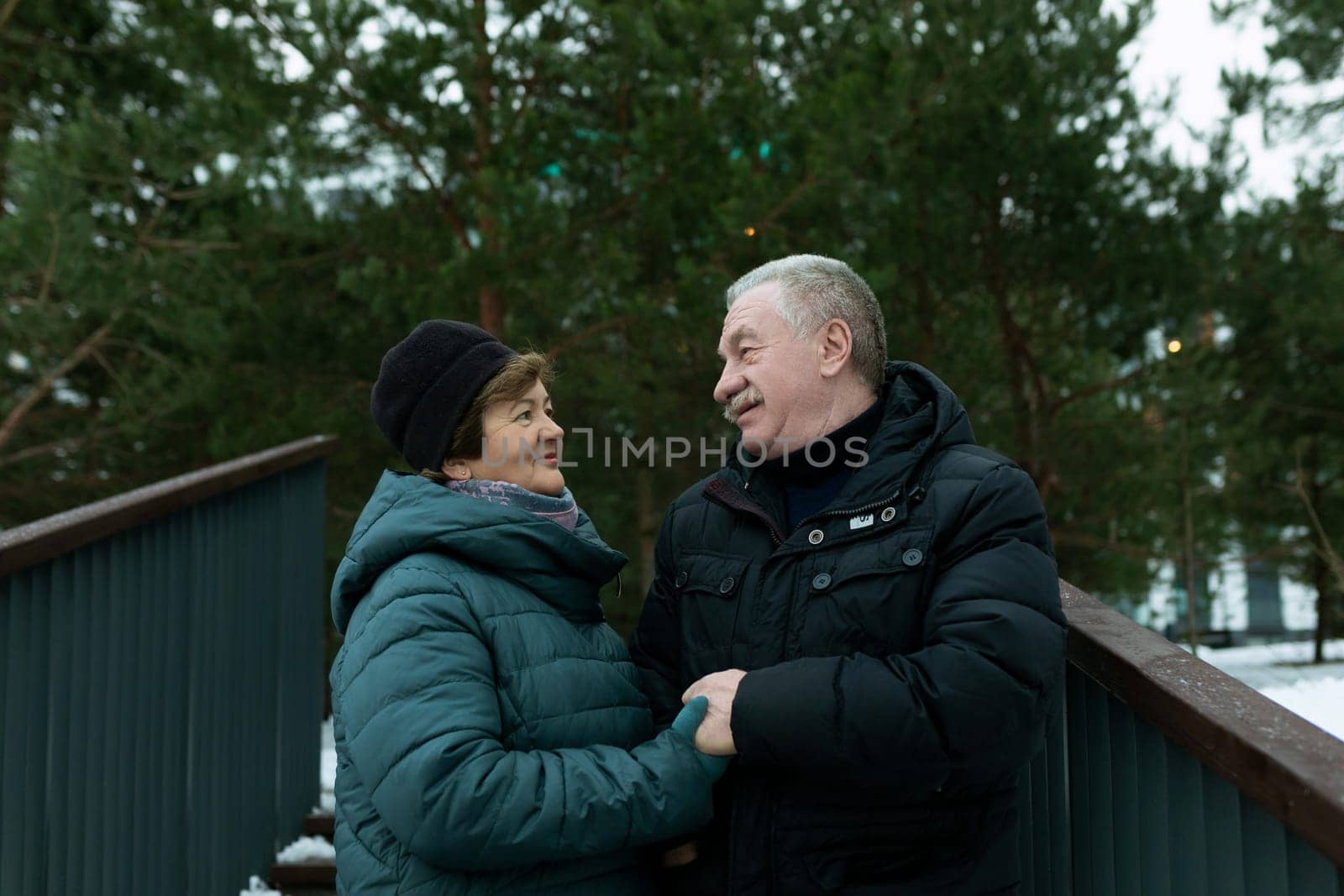 Cute retired couple walking in the park and enjoying a conversation by TRMK