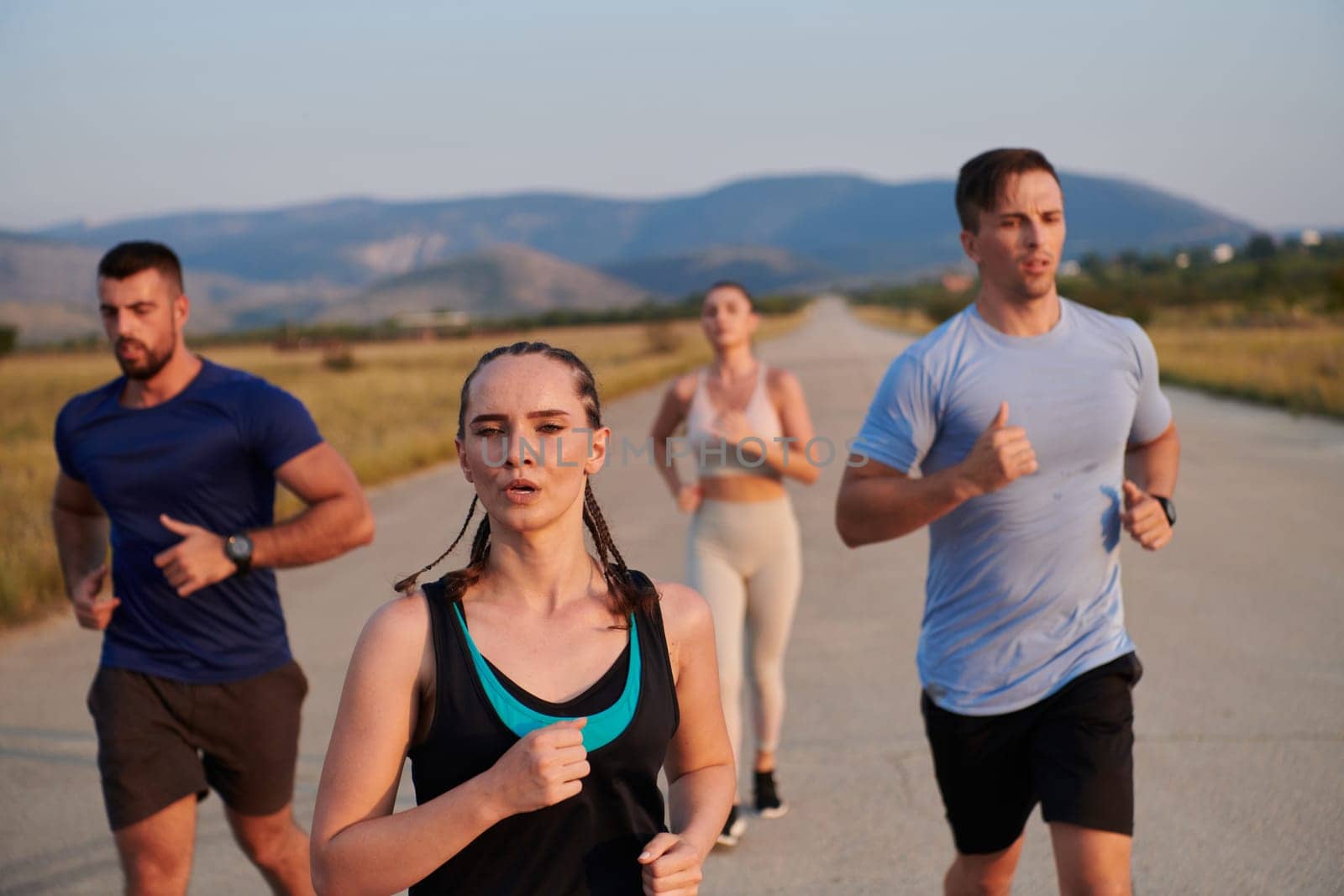 A group of friends maintains a healthy lifestyle by running outdoors on a sunny day, bonding over fitness and enjoying the energizing effects of exercise and nature by dotshock