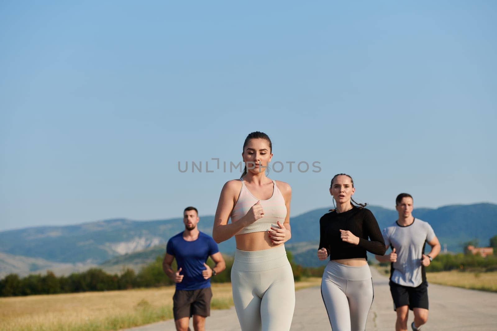 A group of friends maintains a healthy lifestyle by running outdoors on a sunny day, bonding over fitness and enjoying the energizing effects of exercise and nature by dotshock