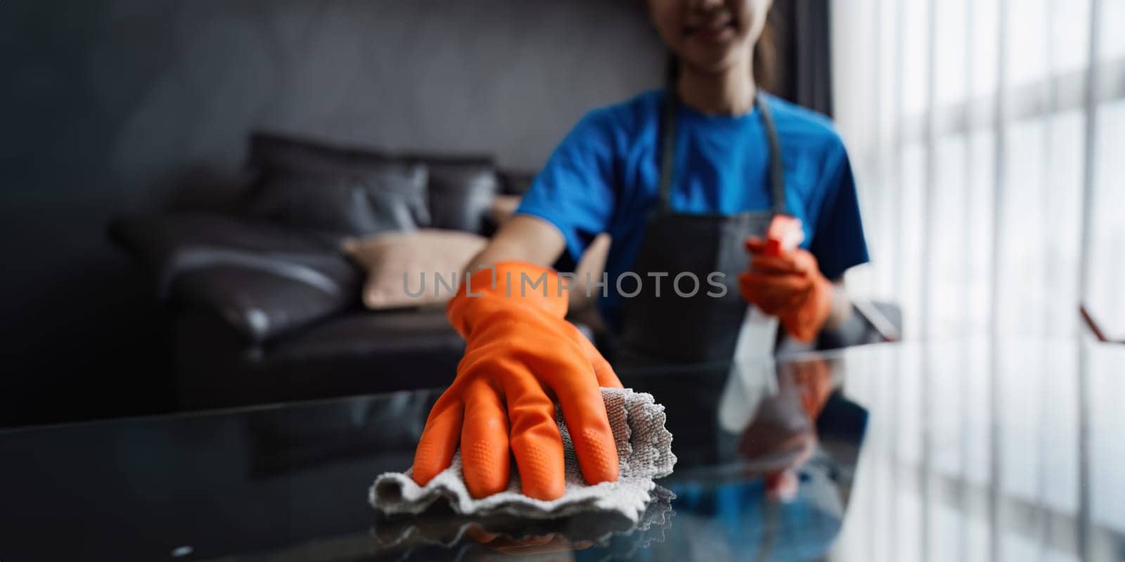 Housekeeping woman wiping the table in the living room. House cleaning service concept by itchaznong