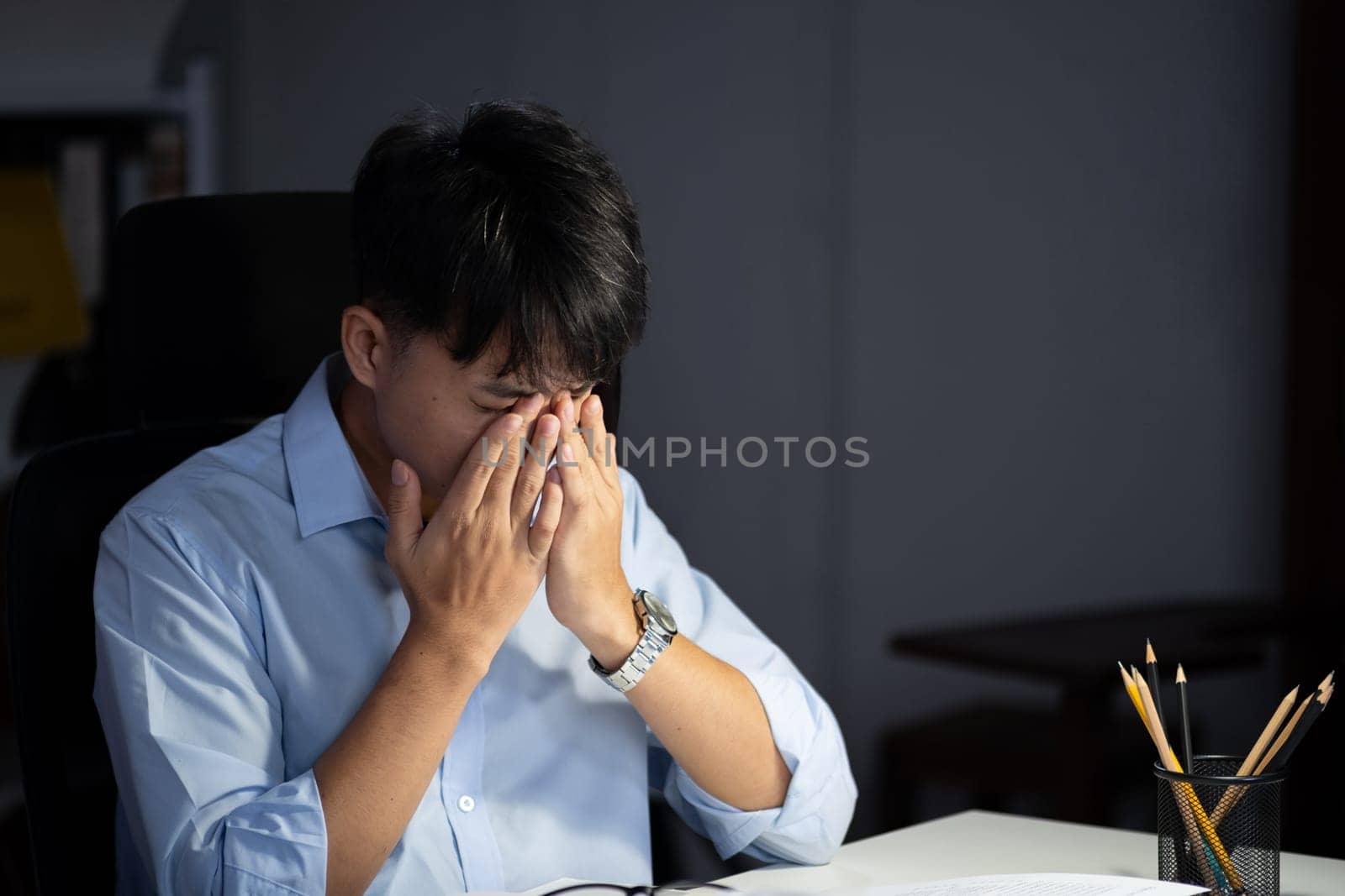 Businessman working overtime at his office makes his eyes tired. by ijeab