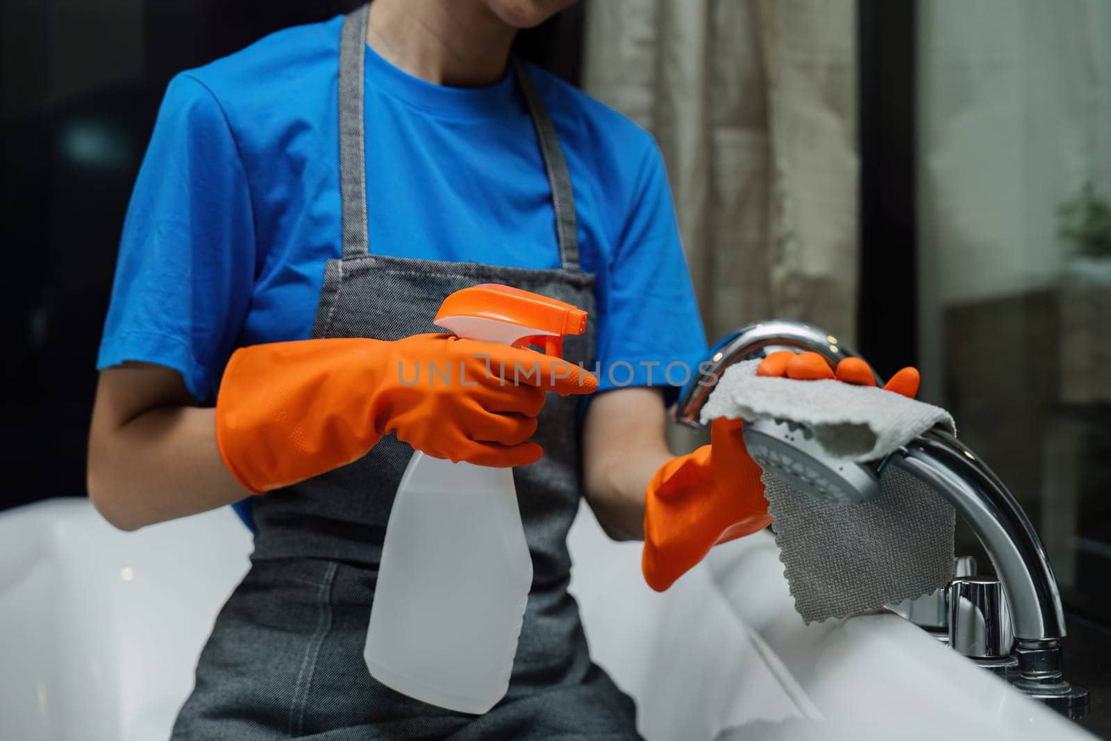 Cleaning online service. yong woman housekeeper cleaning bathtub in bathroom with a cloth. House cleaning service concept.