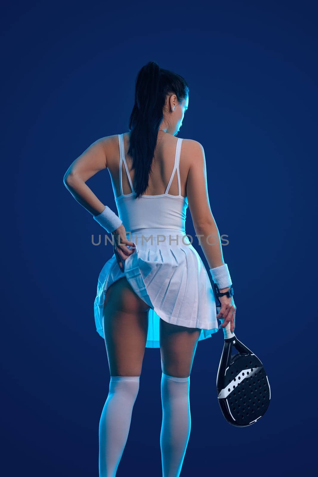 Padel tennis player with racket. Girl teenager athlete with racket on court with neon colors. Sport concept. Download a high quality photo for the design of a sports app or betting site